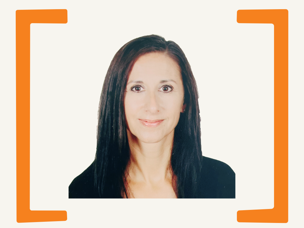 Portrait of a woman with straight dark hair, wearing a black top, smiling against a plain white background.